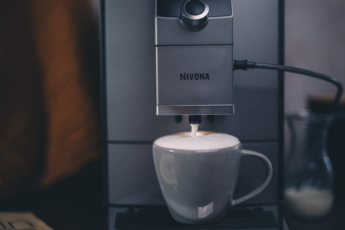 Milchschaum läuft aus der Nivona NICR 7'95 in eine graue Tasse