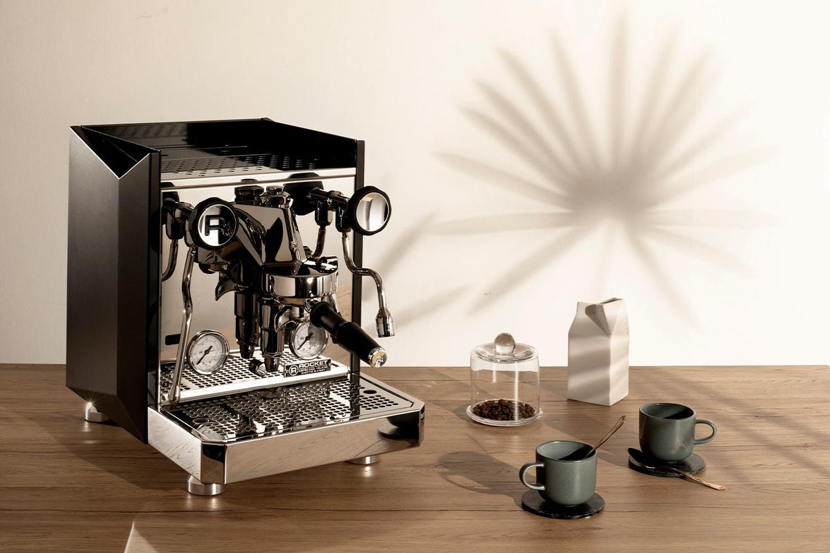 Rocket Giotto FAST in Schwarz auf einem Holztisch mit Espressotassen